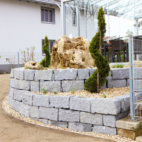 Granit Trockenmauer mit Quellstein und Formgehölzen