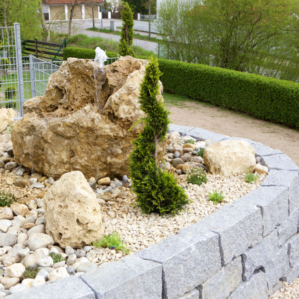 Granit Trockenmauer mit Quellstein und Formgehölzen